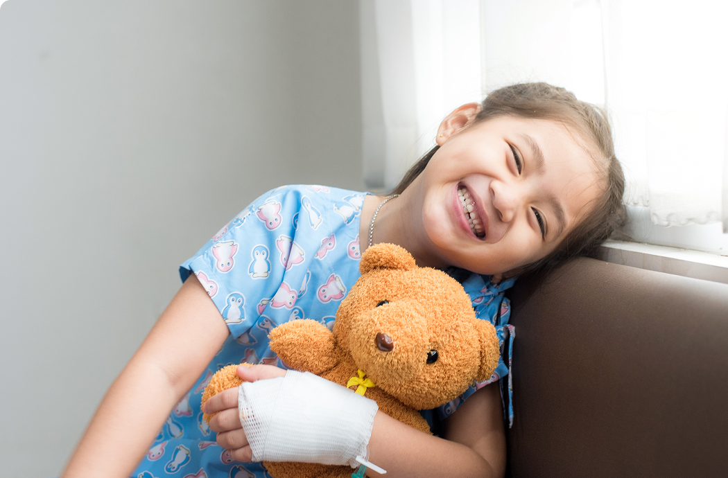 A young girl holding a teddy bear and smiling at the camera